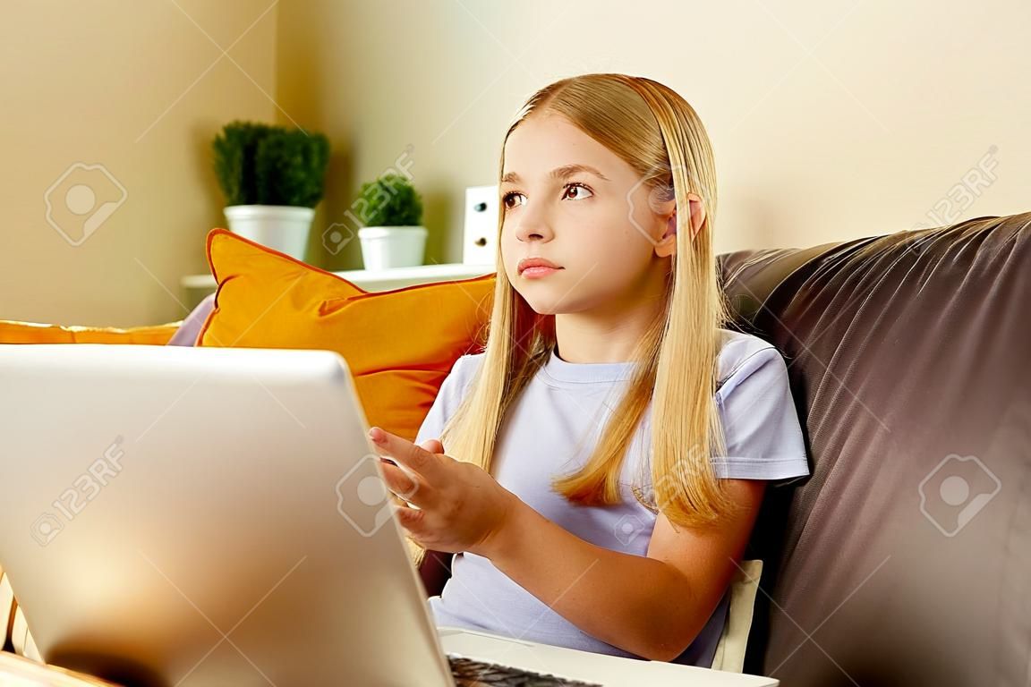 blonge hair little girl using a laptop,doing homework at home.Back to school concept
