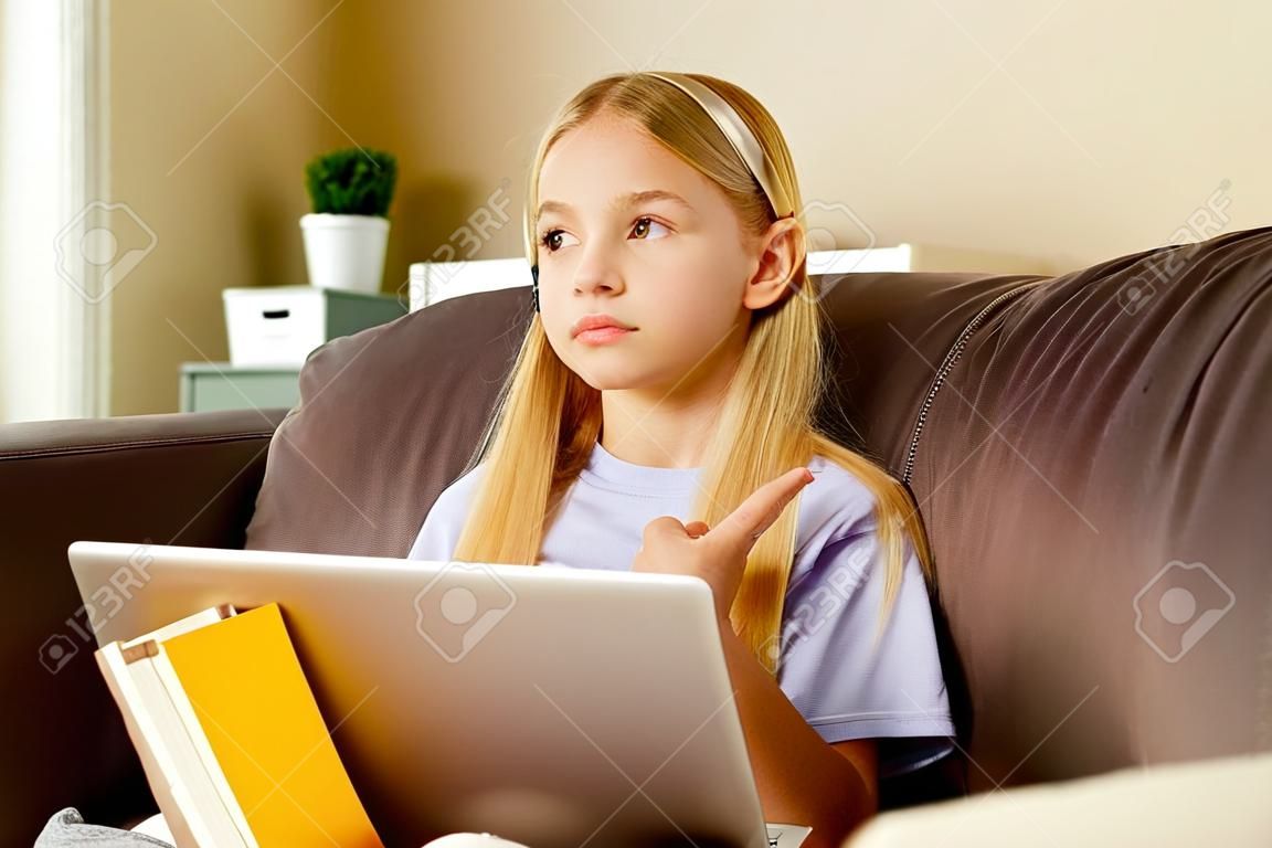 blonge hair little girl using a laptop,doing homework at home.Back to school concept