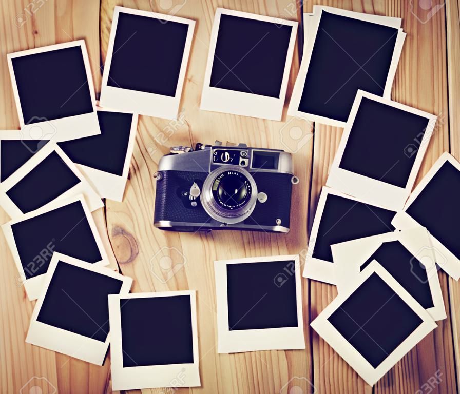 Vintage-Kamera und viele leere Bilderrahmen auf Holztisch. Draufsicht Foto