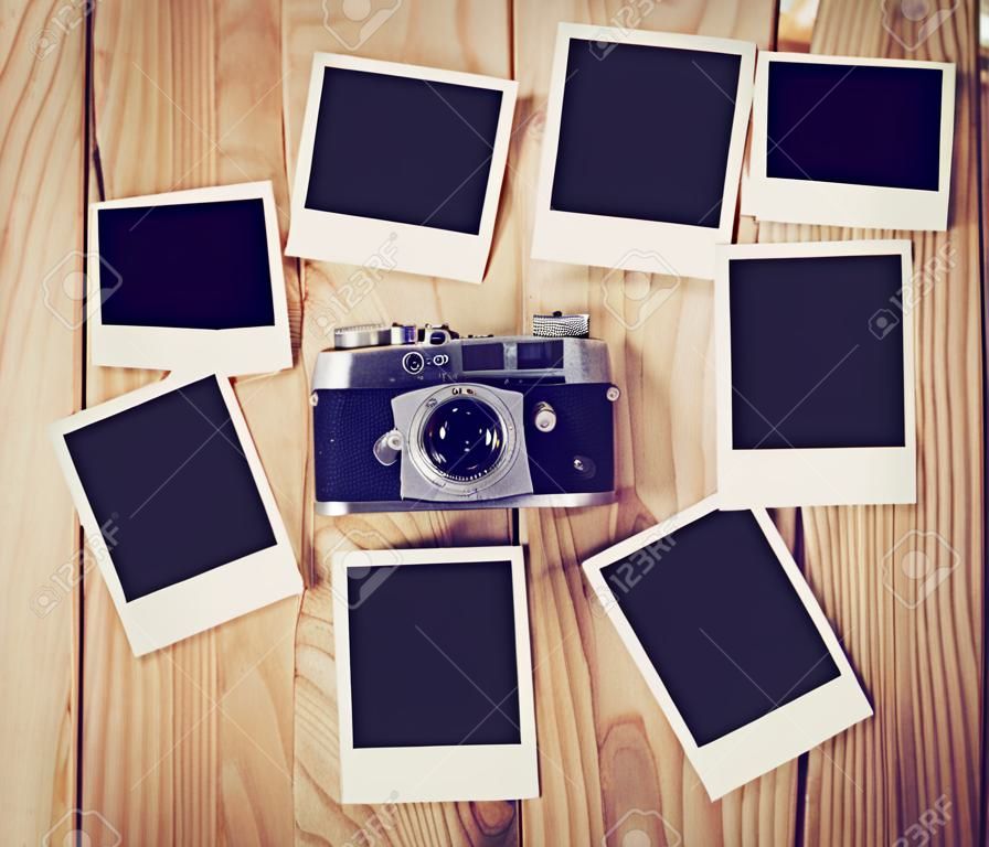 Vintage-Kamera und viele leere Bilderrahmen auf Holztisch. Draufsicht Foto