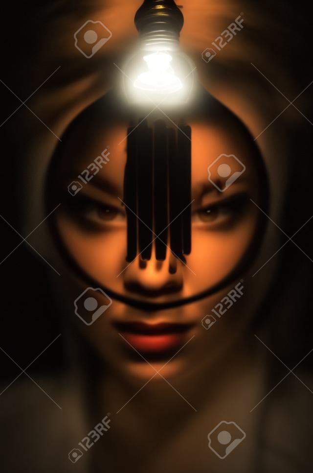 Mysteriöses Foto einer Frau mit Glühbirne. Porträt im Dunkeln. Gefährliche Mädchen.