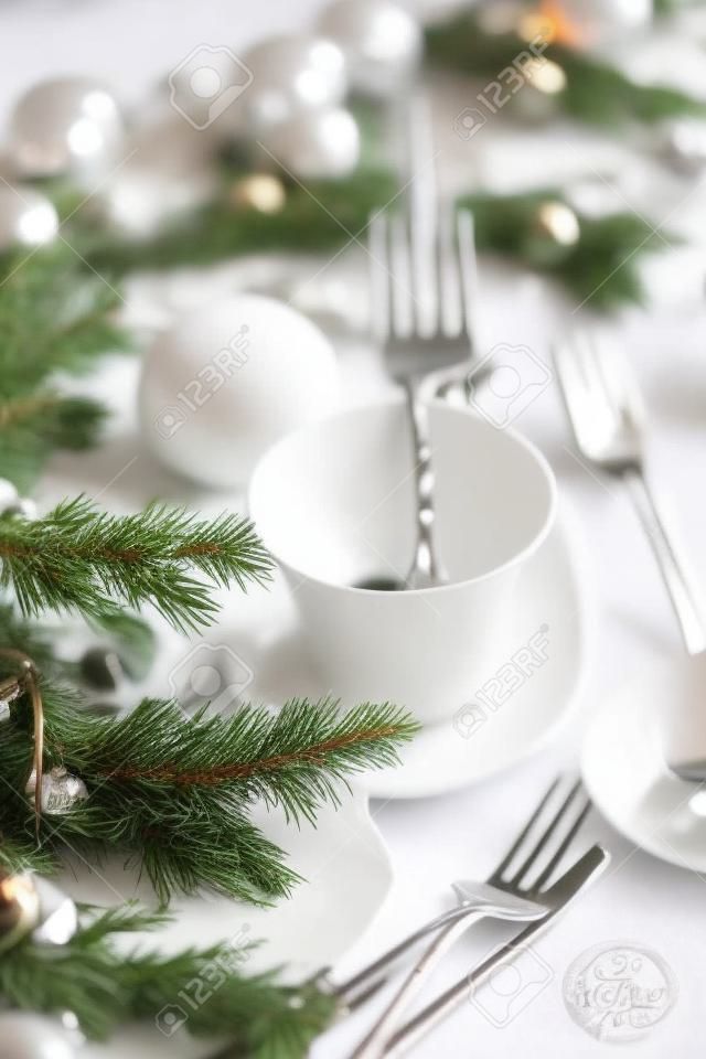 Christmas table setting. Fork and knife in elegant holiday setting with snow and white ornaments