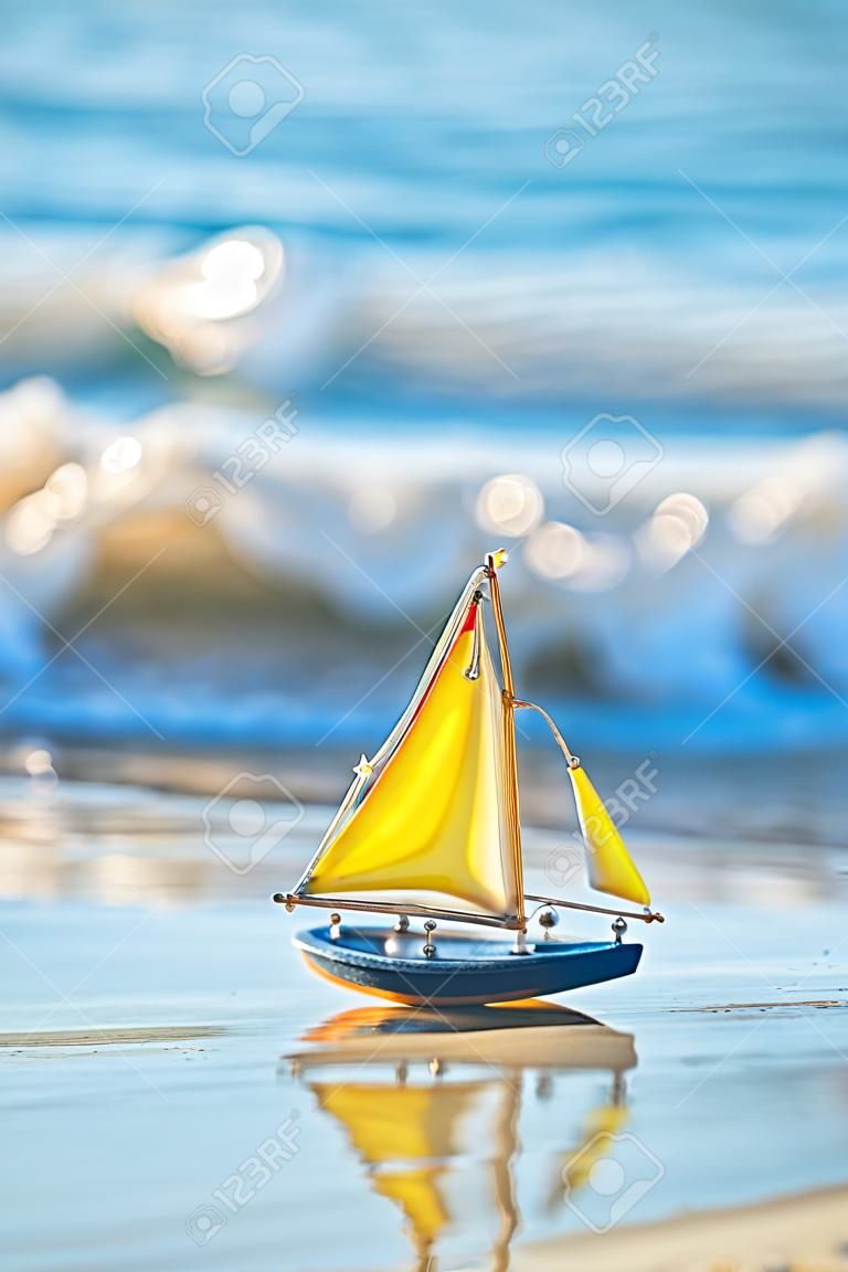 A kis játék hajó áll a homokos tengerparton