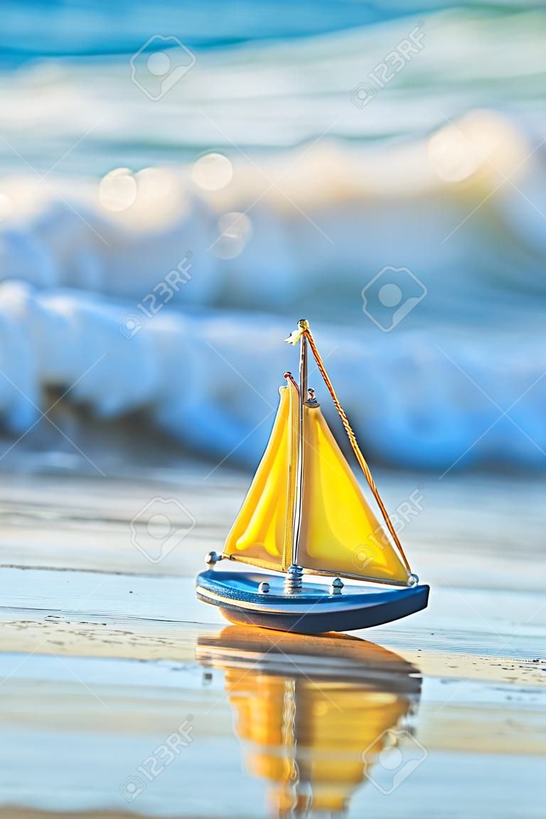 Le petit bateau jouet se dresse sur une plage de sable