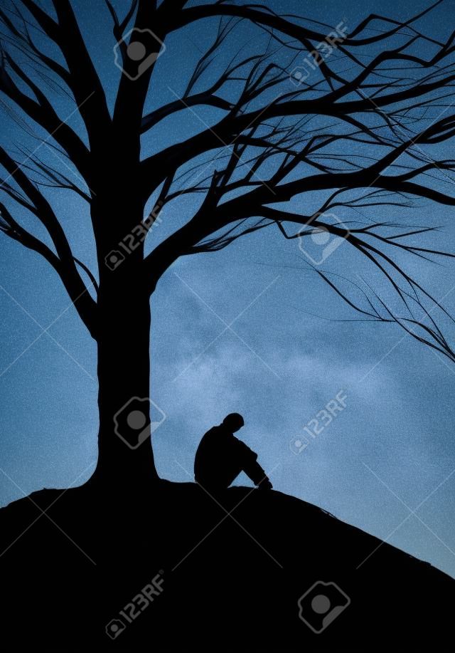 sylwetka człowieka siedzącego pod drzewem