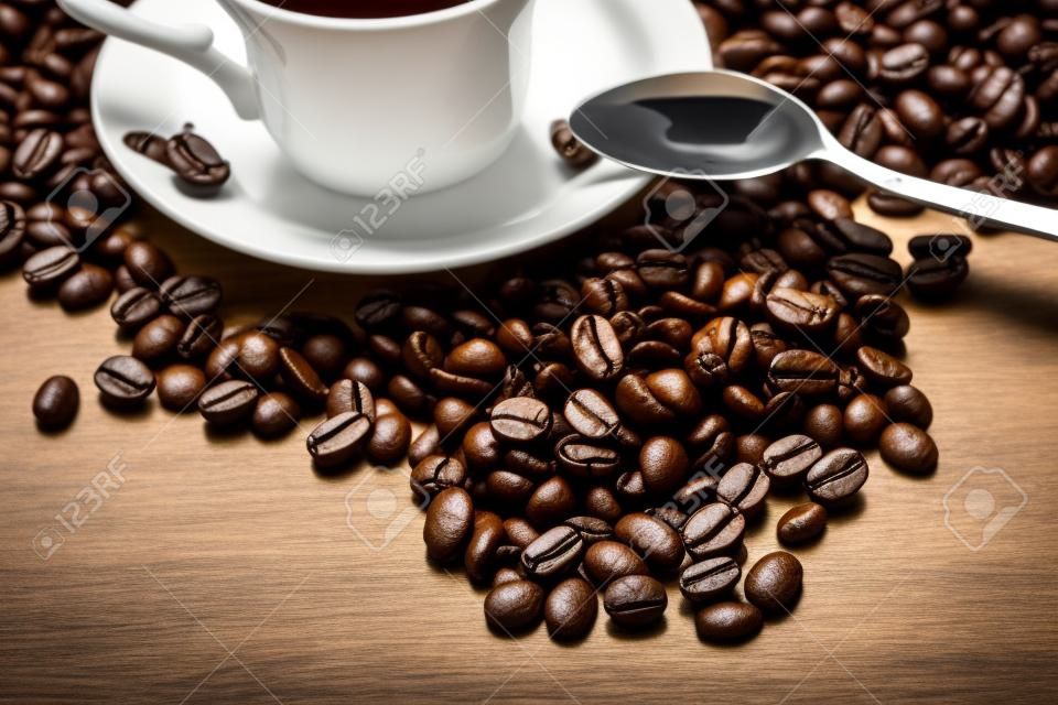 Coup di caffè a fianco con chicchi di caffè sul tavolo in legno a fianco con il cucchiaio