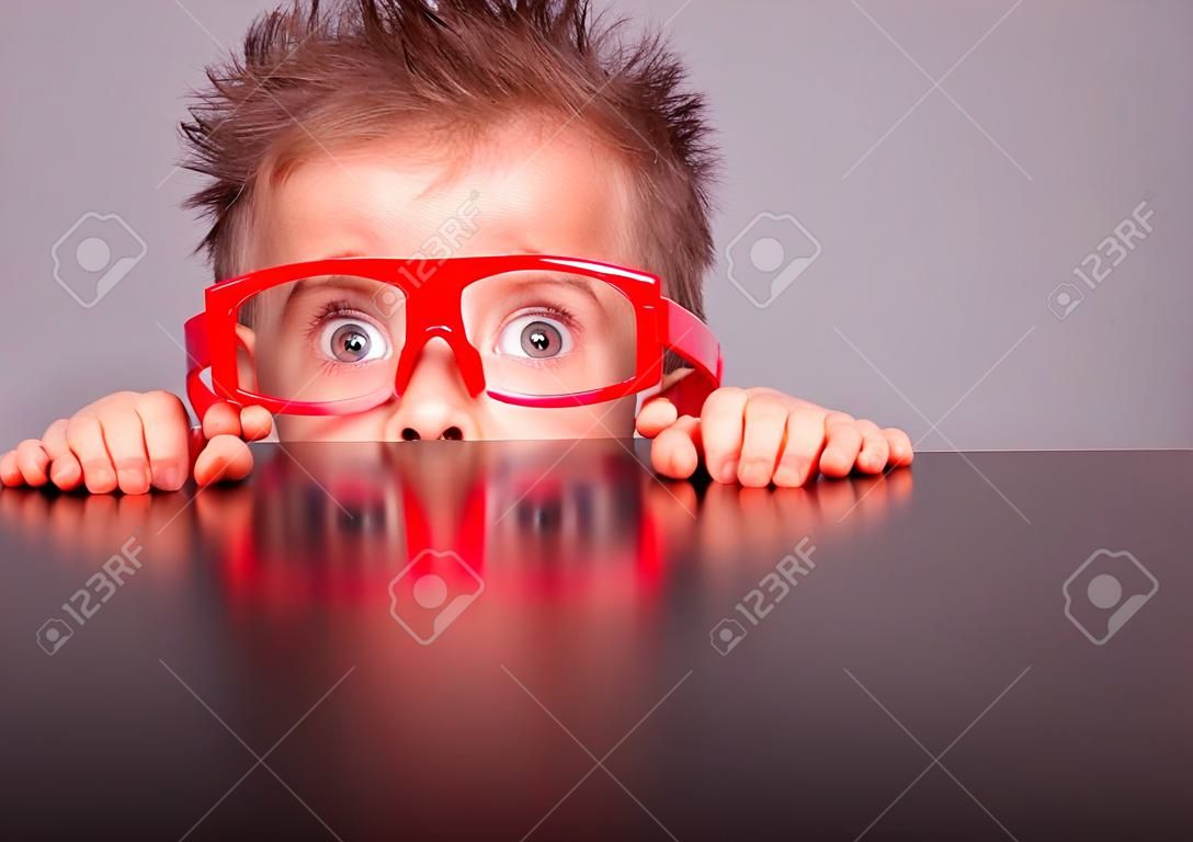 Bir masanın arkasında saklanarak Beş yaşında küçük sevimli çocuk