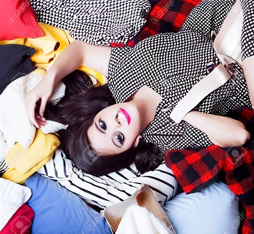 年轻快乐的女人躺在一堆衣服上