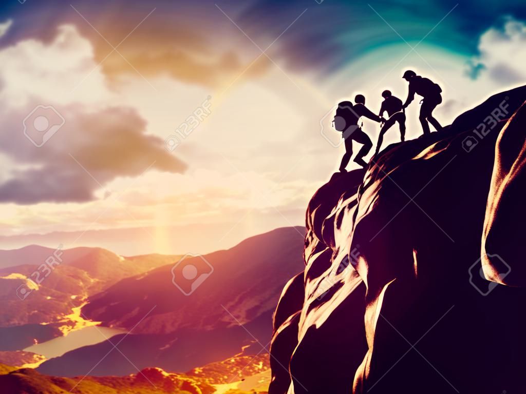 Wandelaars klimmen op rots, berg bij zonsondergang, een van hen geven de hand en helpen om te klimmen Help, ondersteuning, hulp in een gevaarlijke situatie