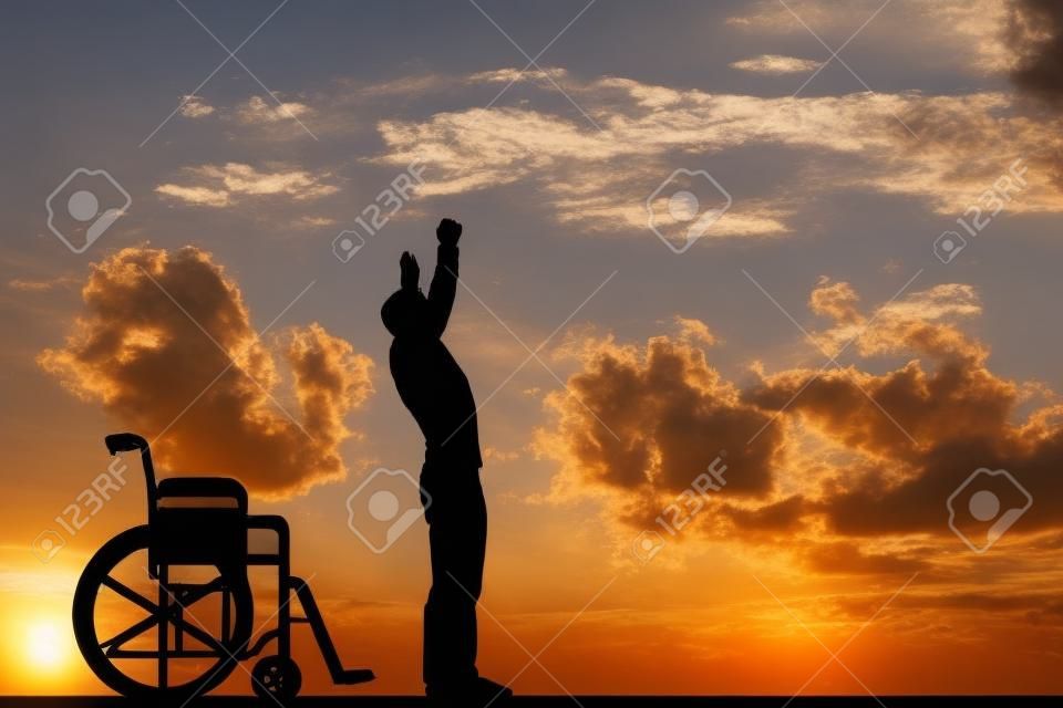 一位殘疾人輪椅從站在日落。治療，康復，醫學奇蹟，希望，保險等積極的概念