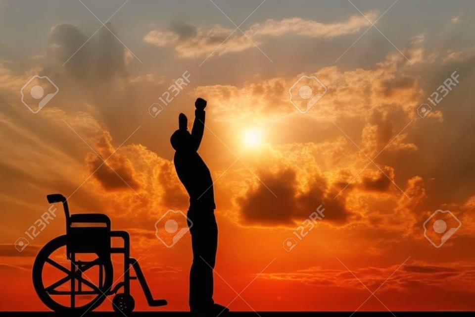 A disabled man standing up from wheelchair at sunset. Positive concept of cure, recovery, medical miracle, hope, insurance etc.