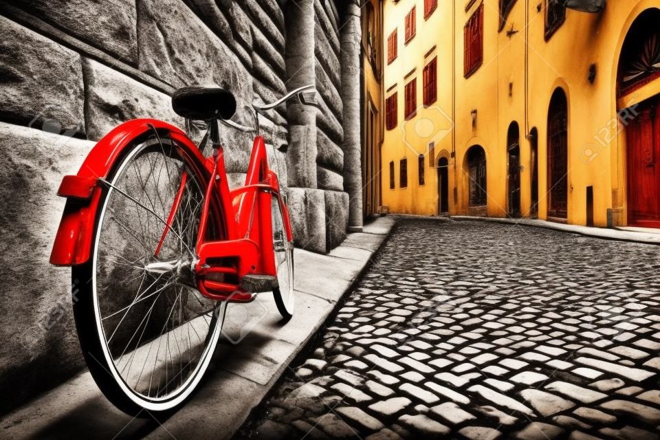 오래 된 마을에서 조약돌 거리에 레트로 빈티지 빨간 자전거. 흑백에서 컬러. 오래 매력적인 자전거 개념입니다.