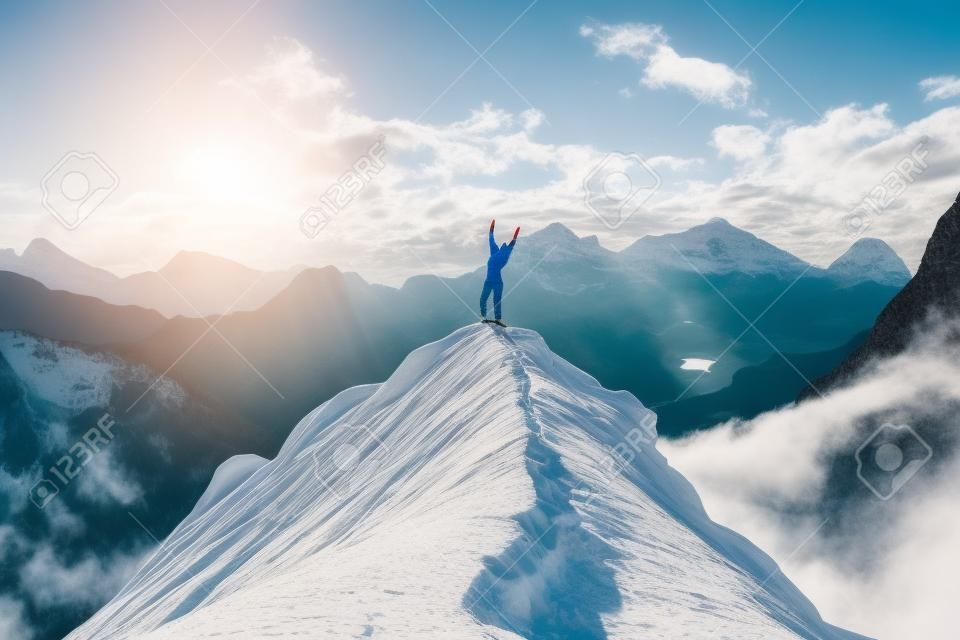 Mujer feliz con las manos arriba en el pico de la montaña disfrutando del éxito, la libertad y el futuro brillante.