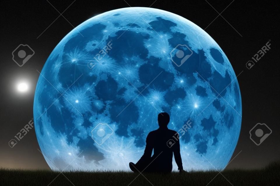Mężczyzna siedzi sam na trawie i patrząc na księżyc. Wyobraź sobie przyszłość. Grafika trójwymiarowa. Elementy tego obrazu dostarczone przez NASA