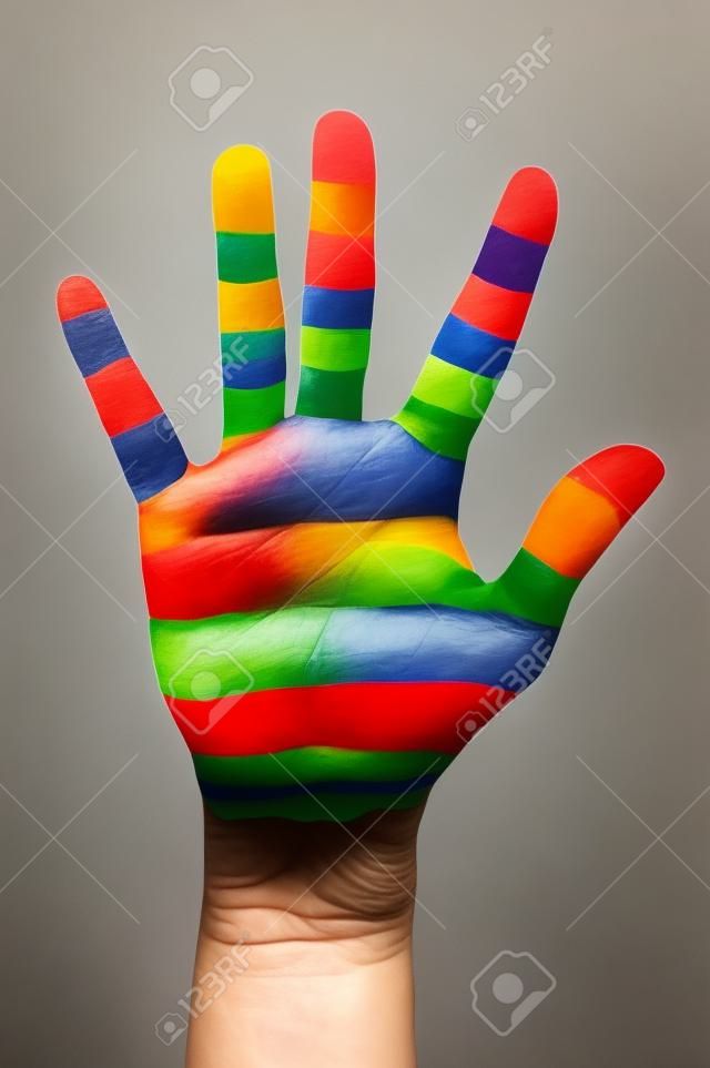 a alguien que muestra la palma de su mano pintada como la bandera del arco iris