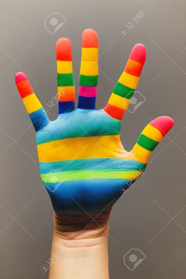 a alguien que muestra la palma de su mano pintada como la bandera del arco iris
