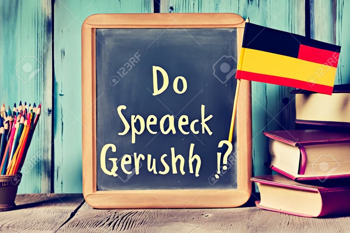 een krijtbord met de vraag sprechen sie deutsch? spreek je Duits? geschreven in het Duits, een pot met potloden, sommige boeken en de vlag van Duitsland, op een houten bureau