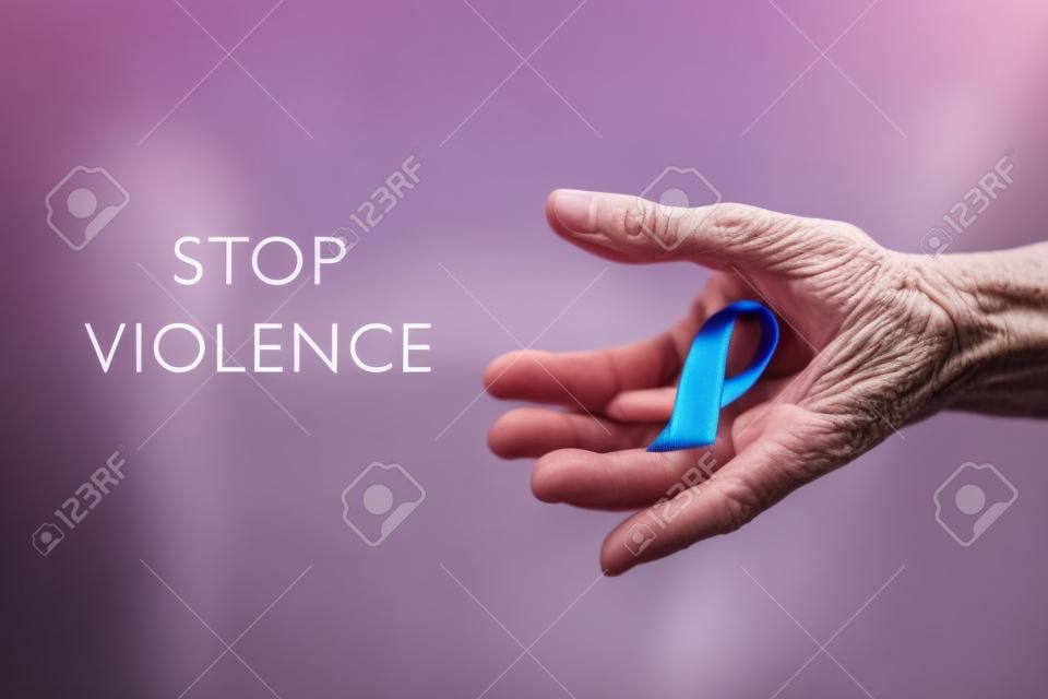 Closeup de uma mulher caucasiana sênior com uma fita roxa na mão, para a consciência sobre a inaceitabilidade da violência contra as mulheres