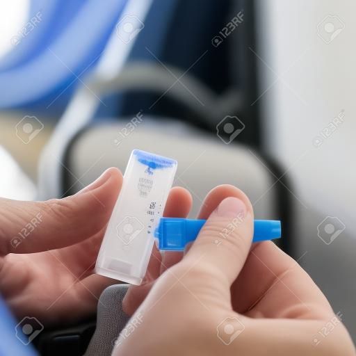 cierre de un joven caucásico en el aeropuerto colocando su propia muestra en el dispositivo de prueba de diagnóstico de antígeno covid-19, mientras está sentado en la sala de espera junto a su maleta
