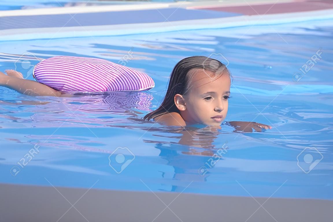아름다운 소녀는 수영장에서 수영하고, 귀여운 소녀는 화창한 날 수영장에서 수영합니다.