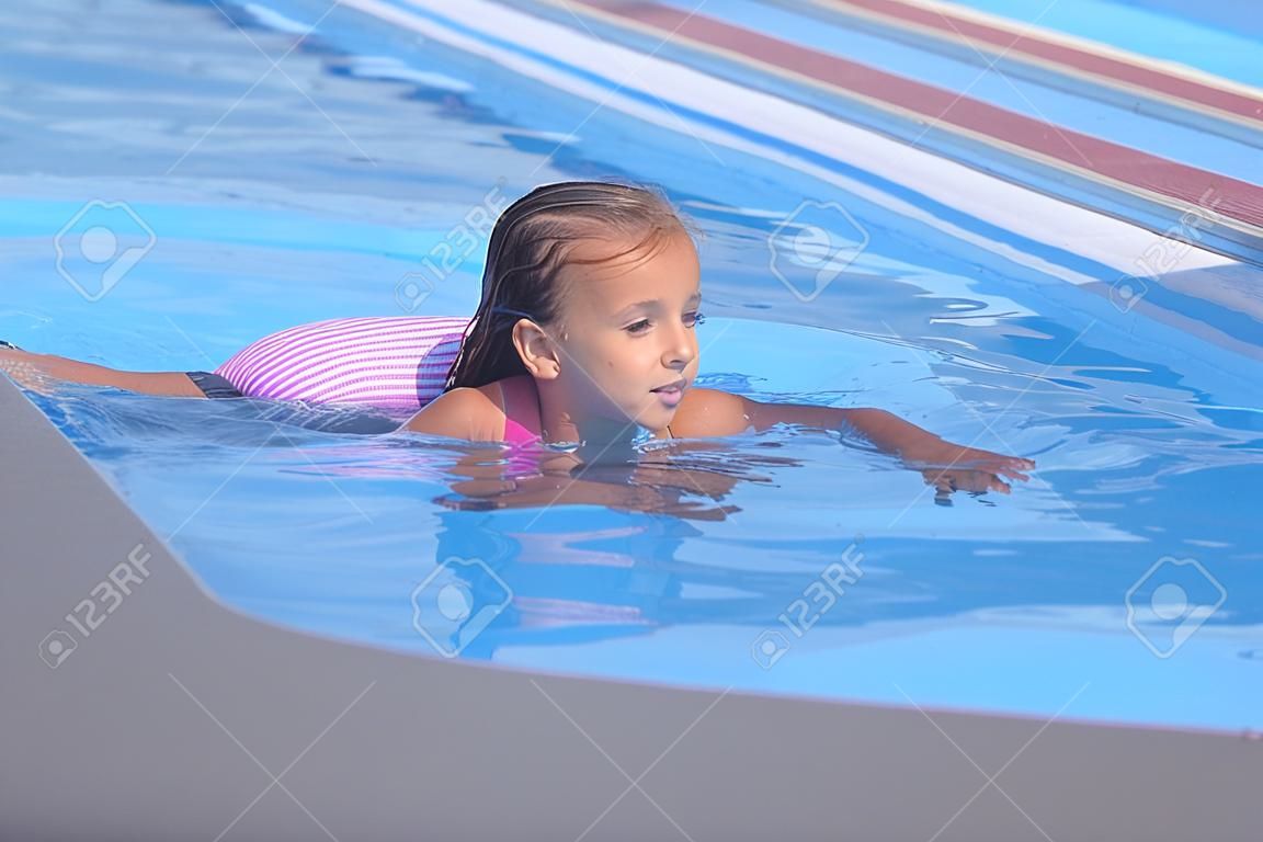 Beautiful little girl swims in the pool , cute little girl in pool in sunny day.little girl .