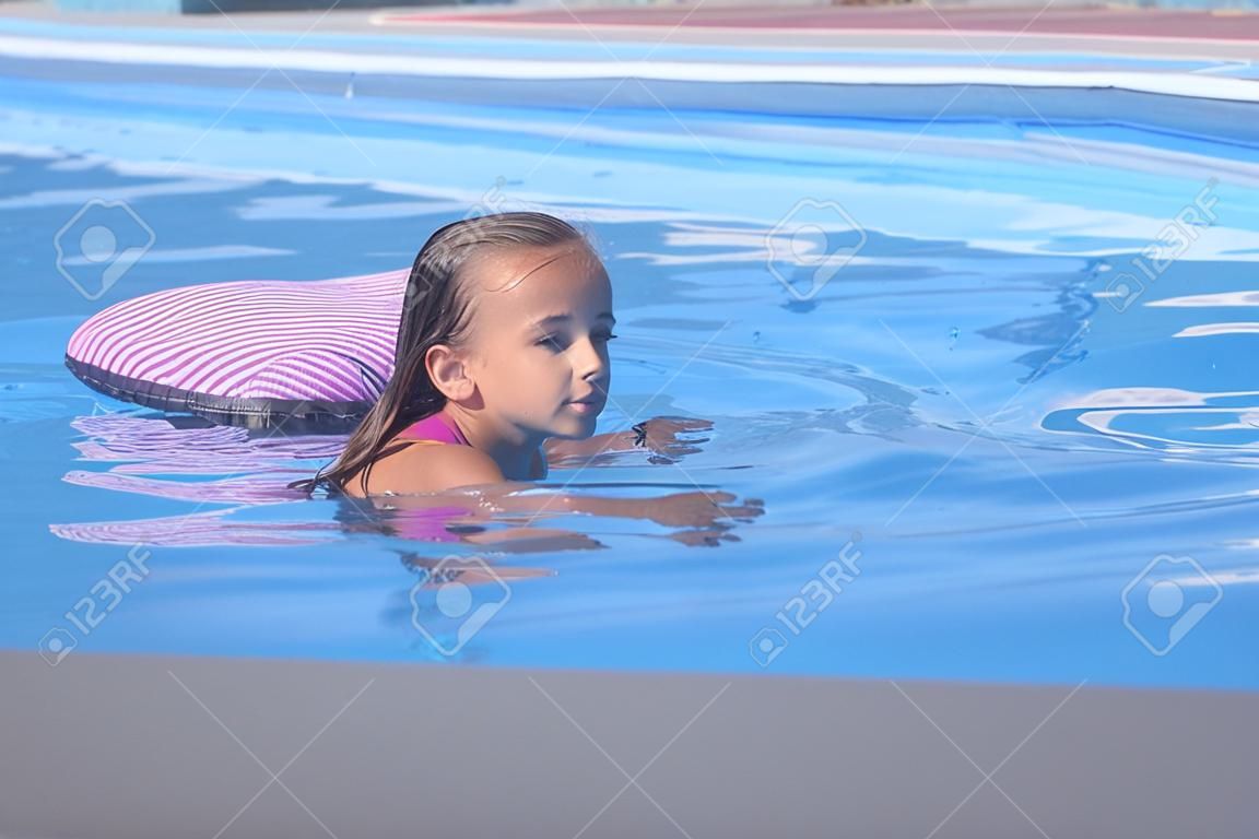 아름다운 소녀는 수영장에서 수영하고, 귀여운 소녀는 화창한 날 수영장에서 수영합니다.