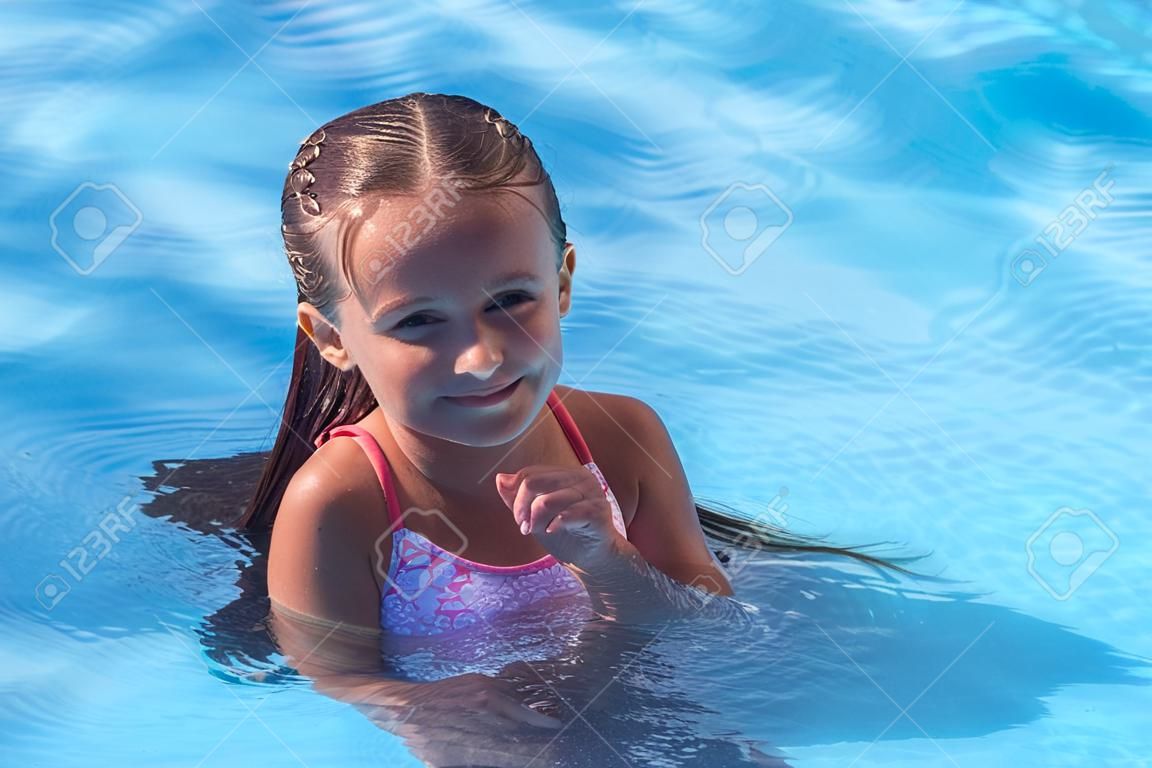 Hermosa niña nada en la piscina, linda niña en la piscina en un día soleado.