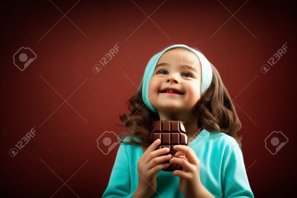 Ragazza e cioccolato. Bambina su uno sfondo chiaro con cioccolato nelle sue mani.
