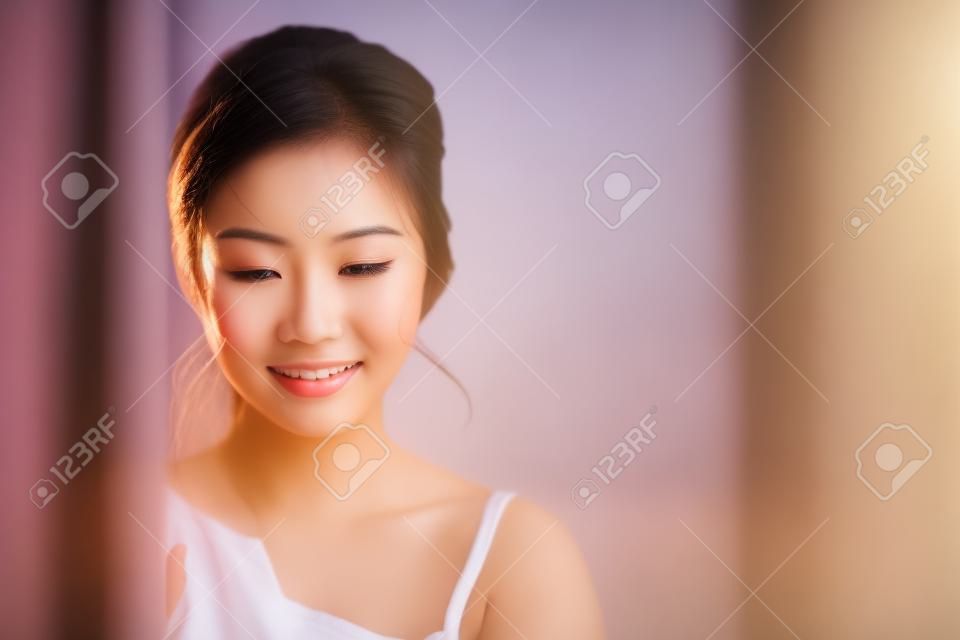 朝日の出で目を覚ましながら窓と笑顔を立たせる美しい若いアジア人女性の肖像画、新鮮さと陽気に満足している少女、ライフスタイルとリラックスコンセプト。