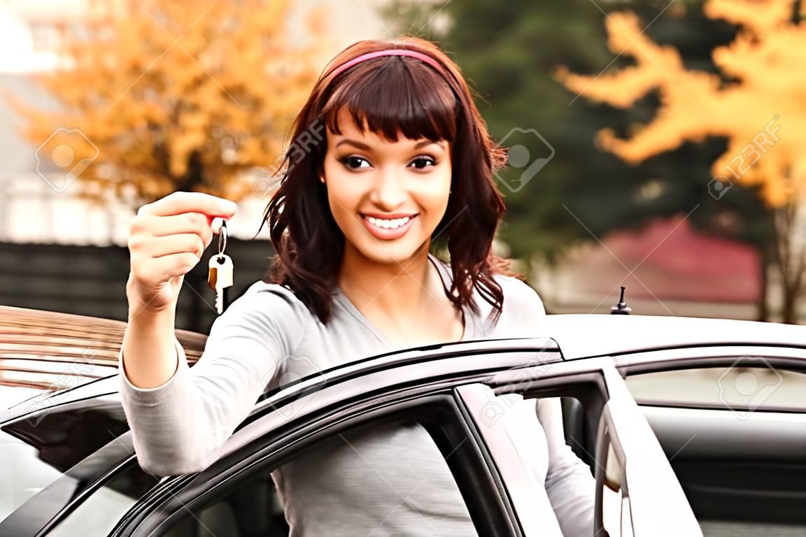 Gelukkige eigenaar van een nieuwe auto, lachend schattig jong meisje met een sleutel