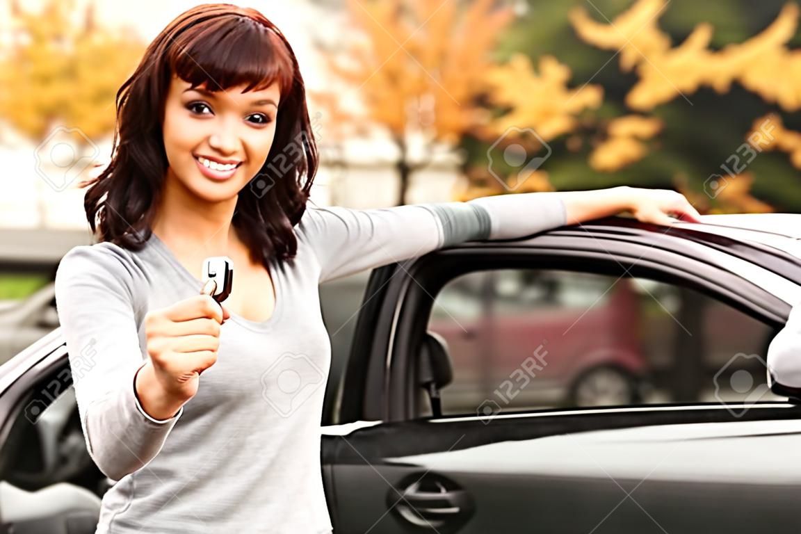 Gelukkige eigenaar van een nieuwe auto, lachend schattig jong meisje met een sleutel