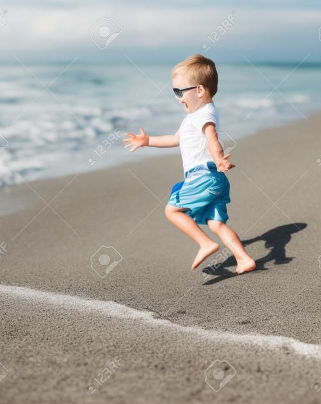 chico adorable corriendo en la playa