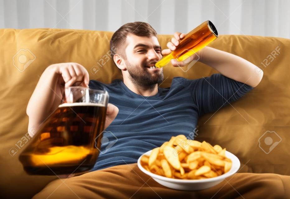 Человек с пивом и чипсами смотреть телевизор дома