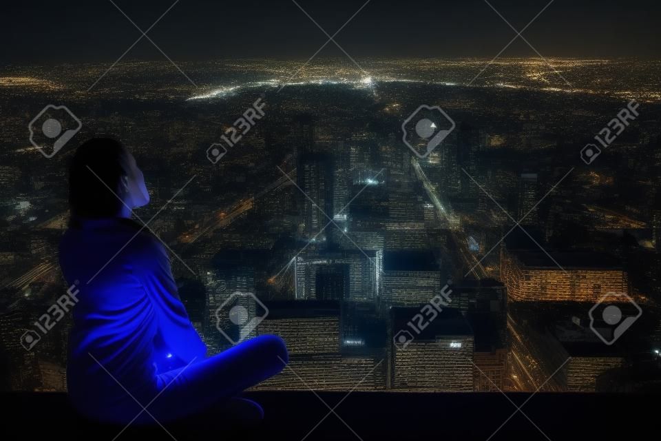 Dalgın kadın çatıda oturan ve gece şehir bakıyor