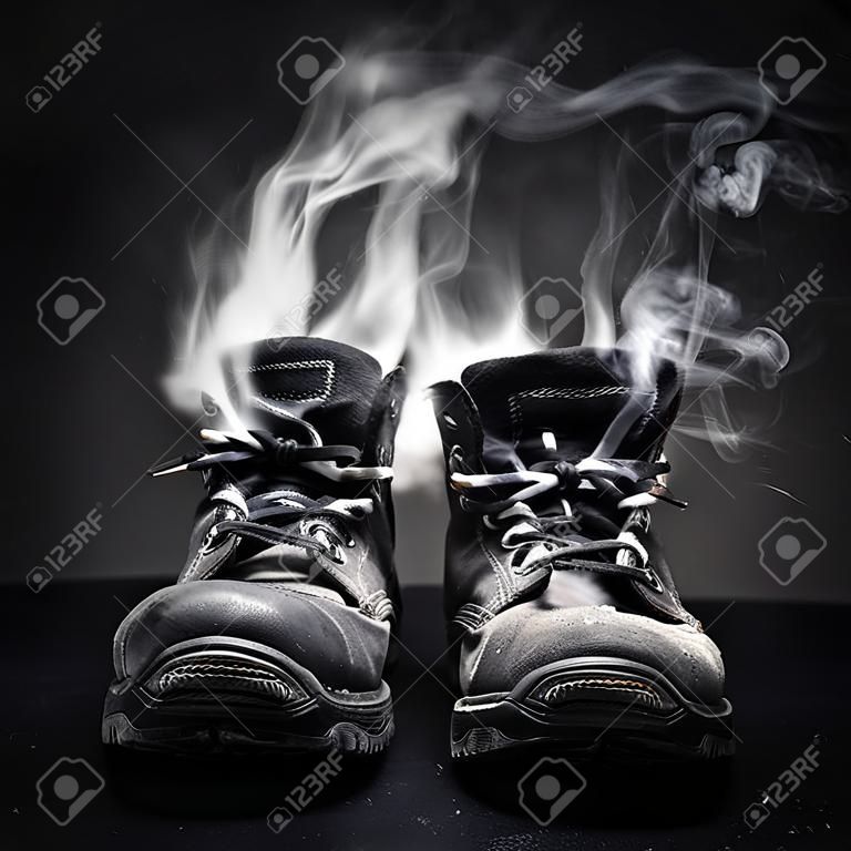 Old black work shoes from which the smoke proceeds