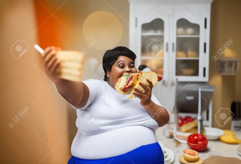 Grosse femme mange un sandwich et fait selfie, obésité