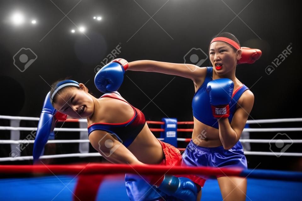Female kickboxers in action, fighting on the ring
