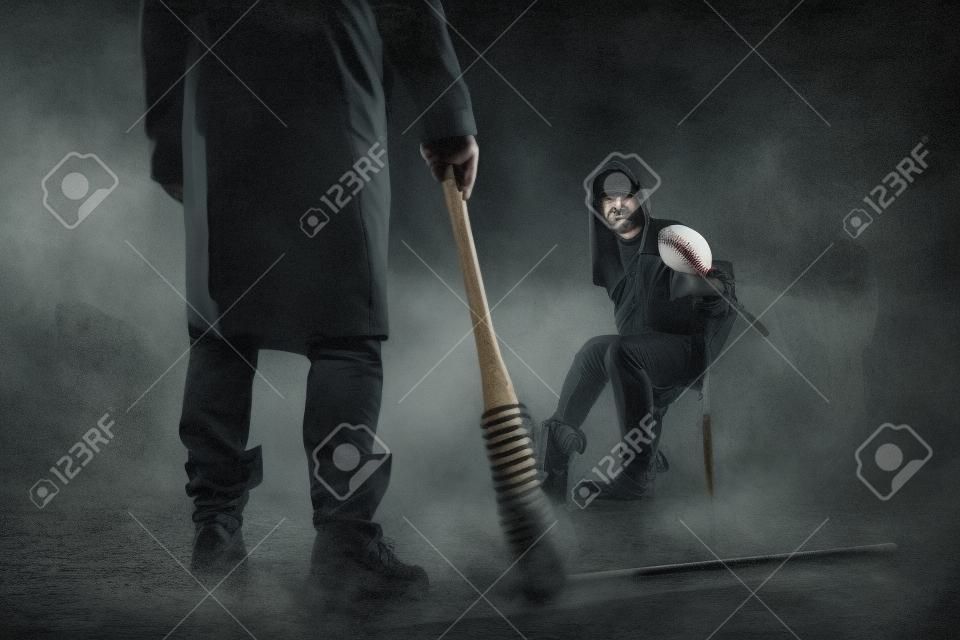 Murderer with baseball bat standing against victim