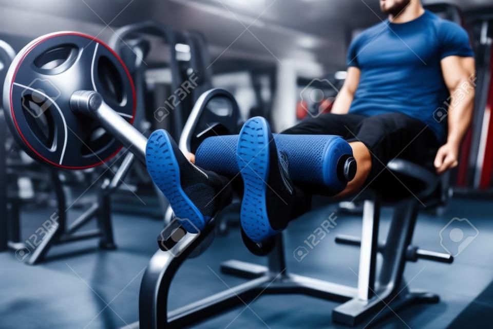 Male person trains legs on exercise machine in gym