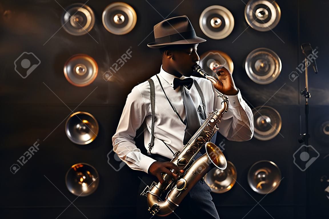 Black jazzman in hat plays the saxophone on stage