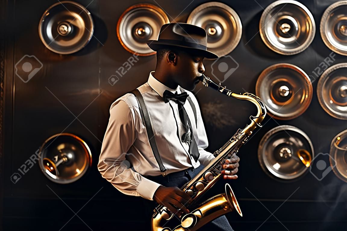 Black jazzman in hat plays the saxophone on stage