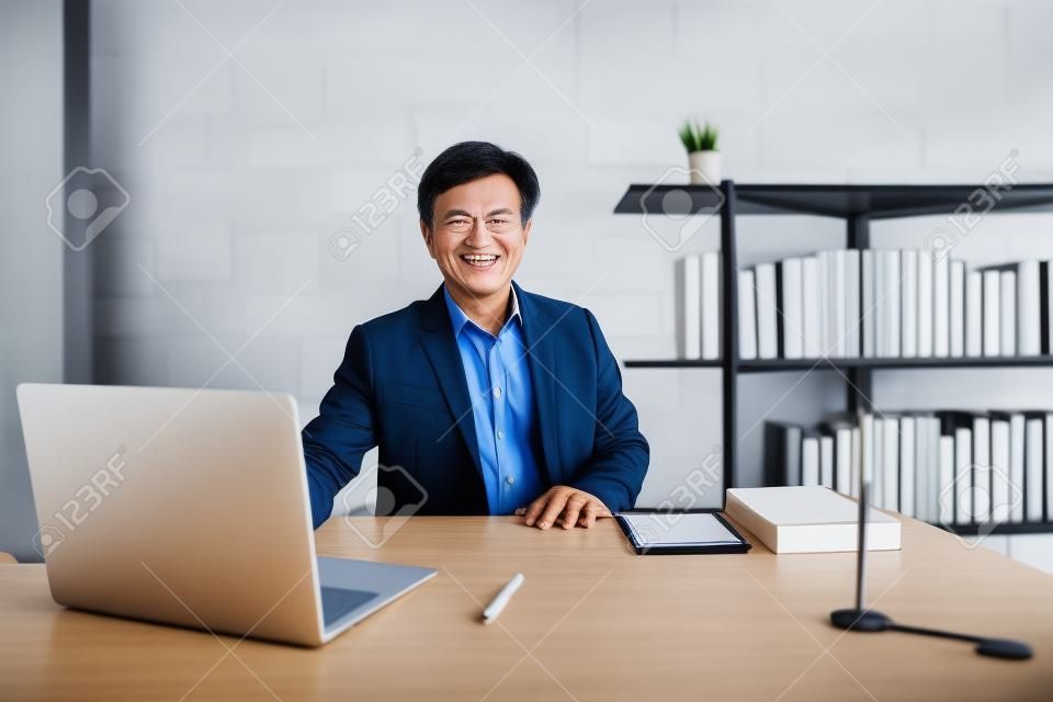 Azjatycki starszy biznesmen, 50-60 lat, pracujący w biurze. Portret inteligentnego dorywczo azjatyckiego starszego dyrektora w jego miejscu pracy. Dyrektor Generalny (CEO) w swoim osobistym pokoju w biurze.