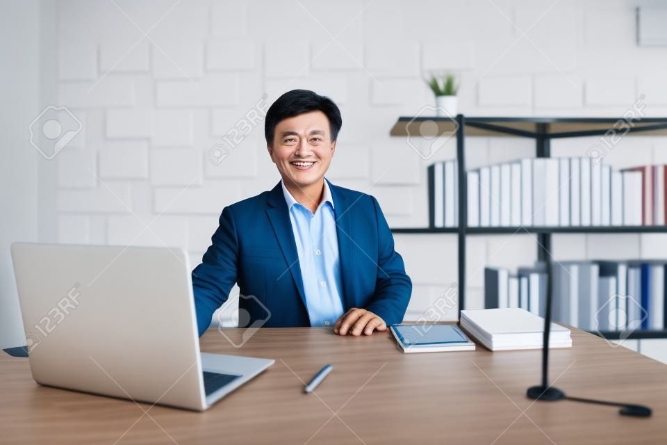 Azjatycki starszy biznesmen, 50-60 lat, pracujący w biurze. Portret inteligentnego dorywczo azjatyckiego starszego dyrektora w jego miejscu pracy. Dyrektor Generalny (CEO) w swoim osobistym pokoju w biurze.