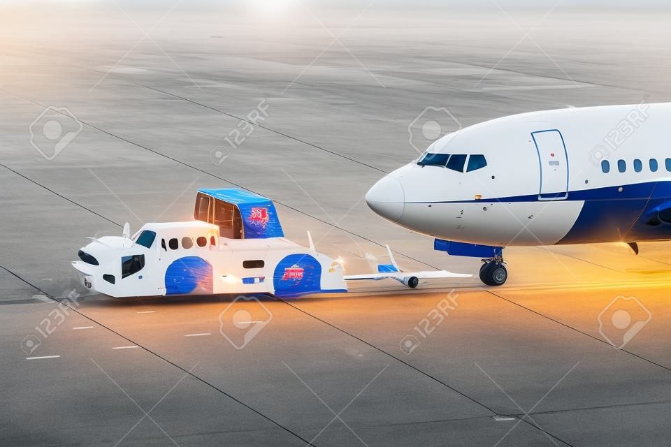 avião na pista do aeroporto com trator pushback anexado ao reboque da engrenagem do nariz do avião por veículo terrestre para portão terminal.