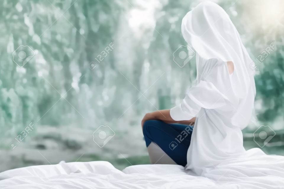 Mooie dame in wit shirt buiten zittend op een bed