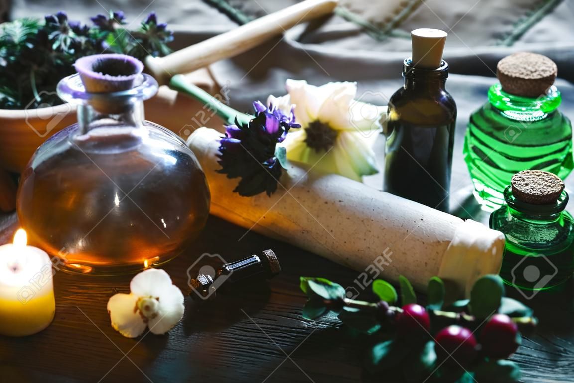 Herbal medicine essential oil and various herbs on a table and ancient recipe scroll. Witchcraft.