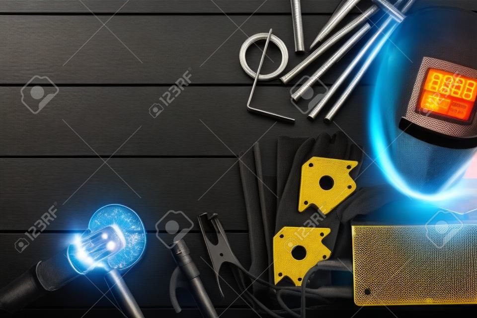 Welding concept background. Metal pieces, welding terminals, magnet holder, electrodes and welding leggings on the workbench.