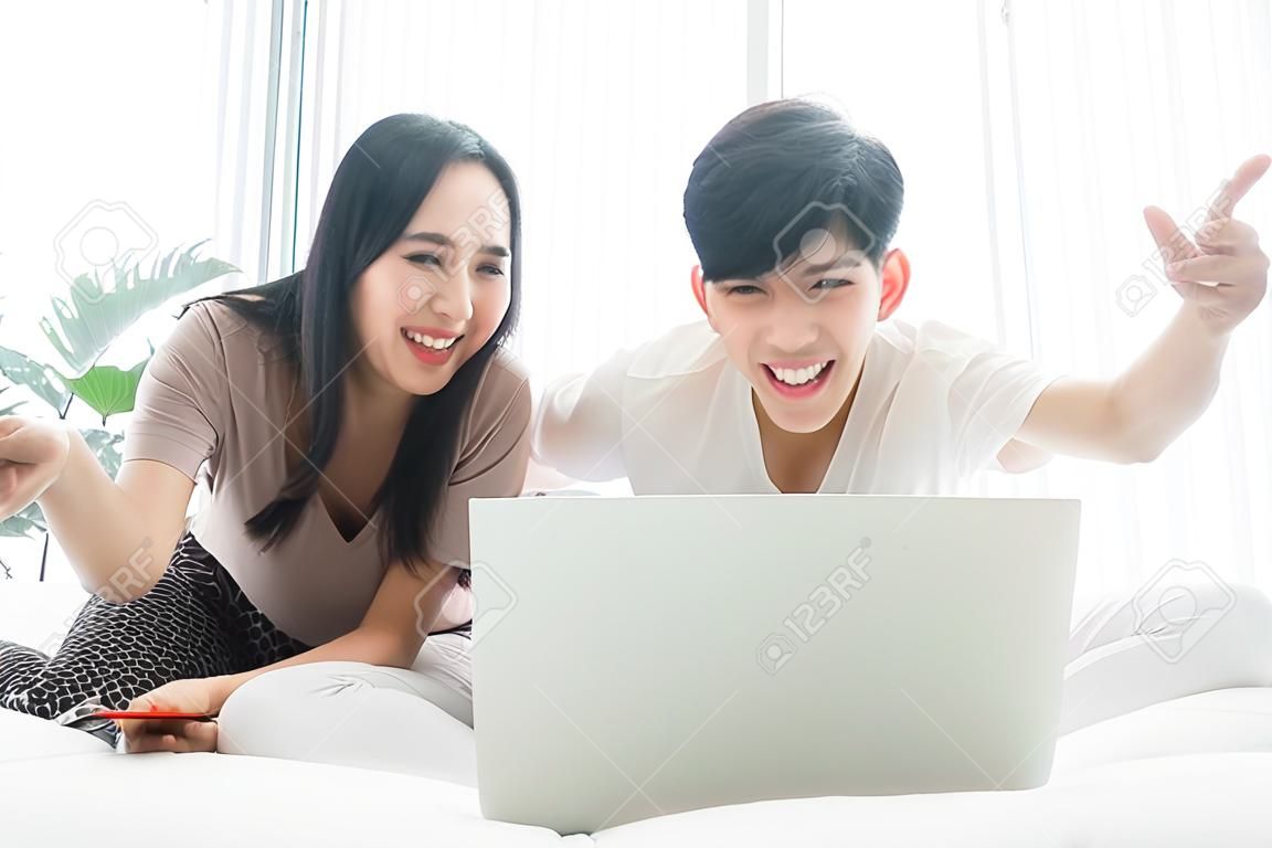 Asian men and women are happily at home. They are using laptops, working and watching news and other TV programs. Staying safe Keep yourself away from society Preventing Covid-19 Infection
