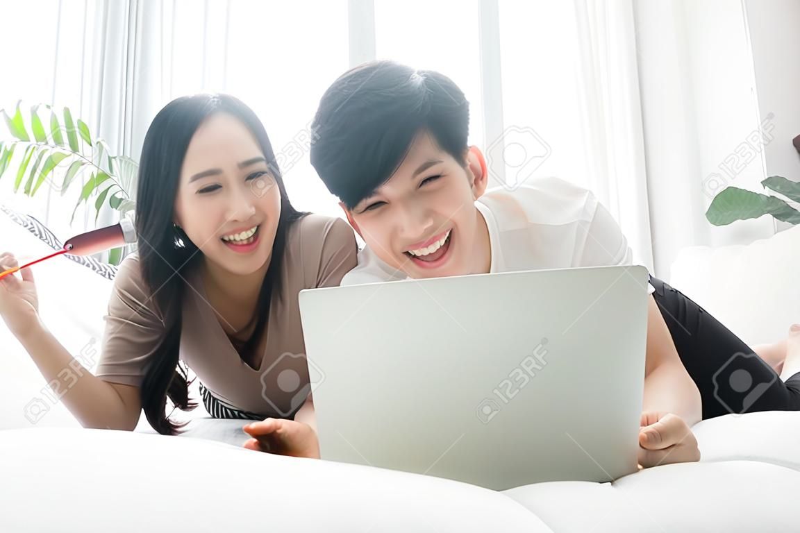 Asian men and women are happily at home. They are using laptops, working and watching news and other TV programs. Staying safe Keep yourself away from society Preventing Covid-19 Infection