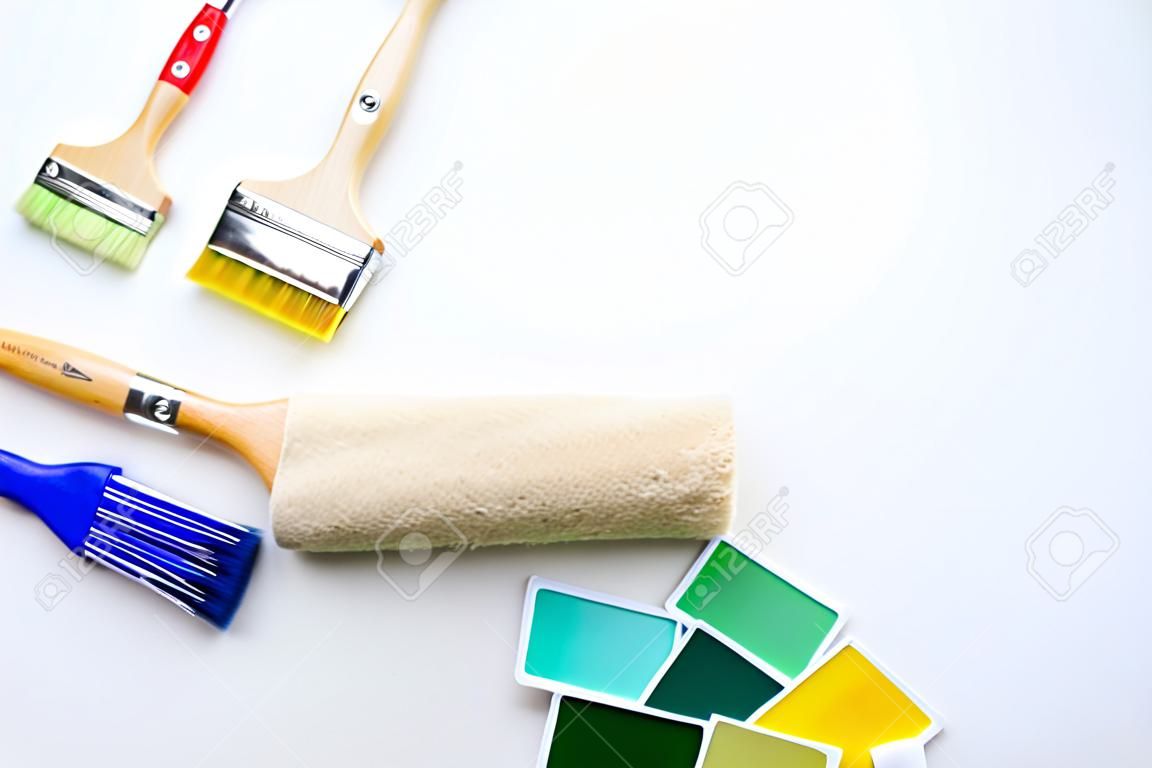 Photo of palette with blue and green colors, roller, brushes